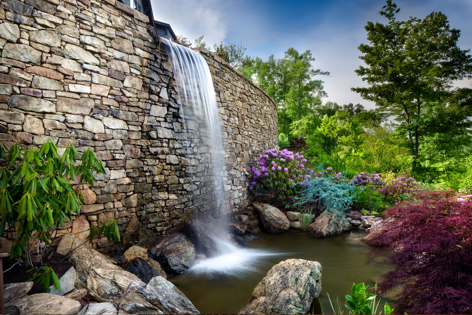 Mountain side outdoor living design with man made waterfall