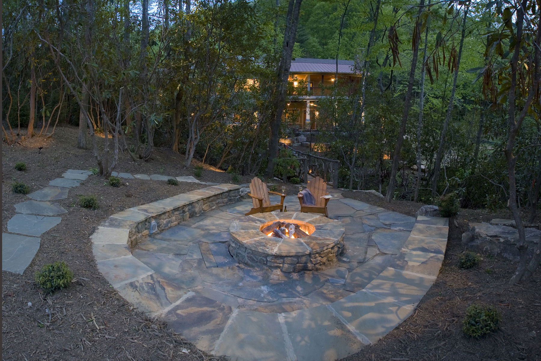 Backyard stone patio with firepit and raised wall for seating