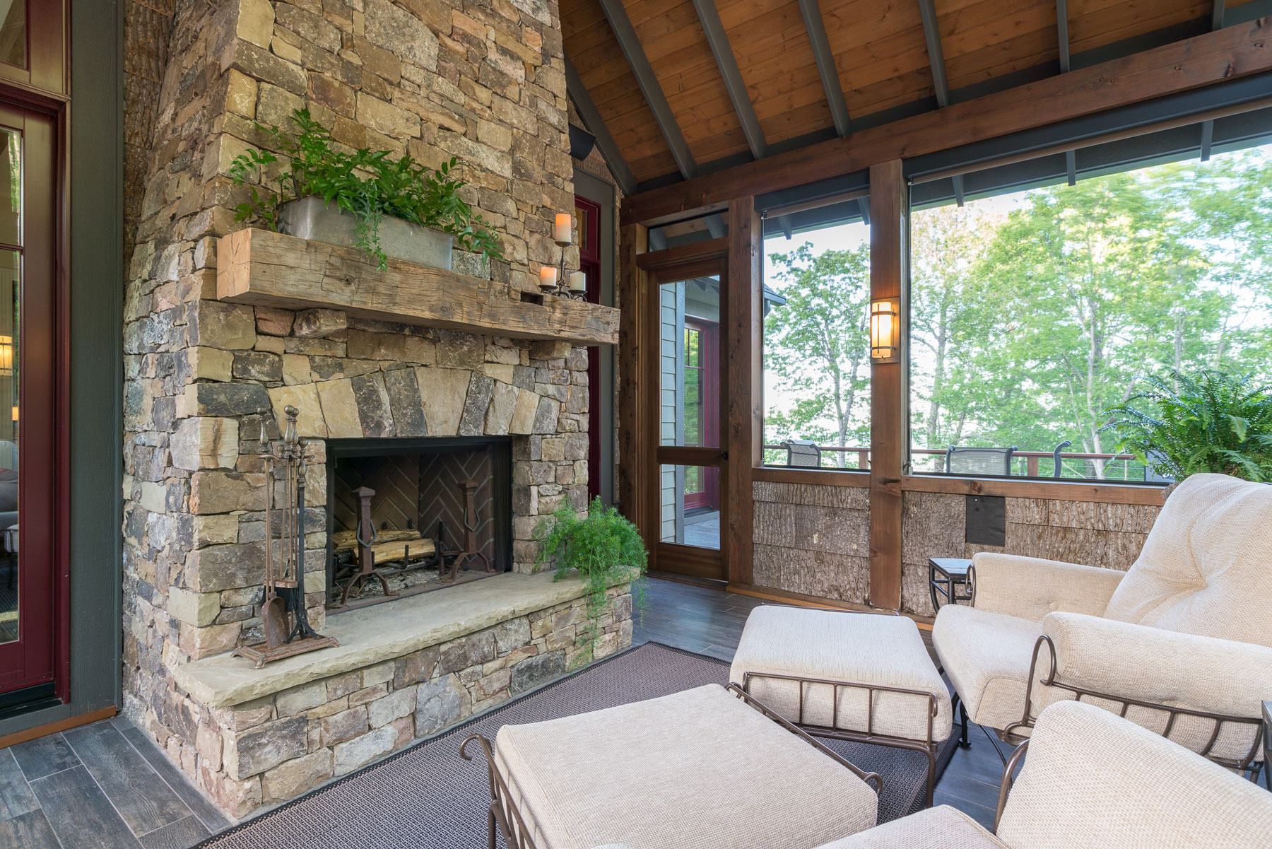 Screened porch with stacked stone fireplace and birch bar walls