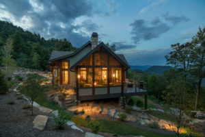 Side of new construction mountain home with screened porch and fireplace on steep slope