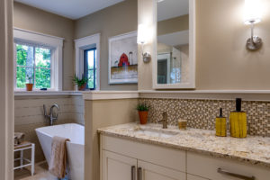 Master bathroom with double vanities and freestanding tub with halfwall separating the two