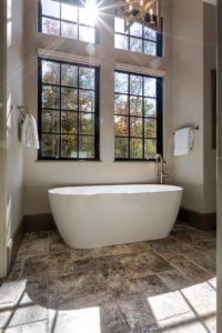 Slipper tub with wall of windows and vaulted ceiling in master bath with silver travertine floor