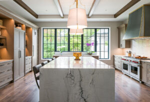 Large center kitchen island with waterfall edge using Everest Pearl quartzite as the countertop, backsplash, and the dramatic waterfall edge