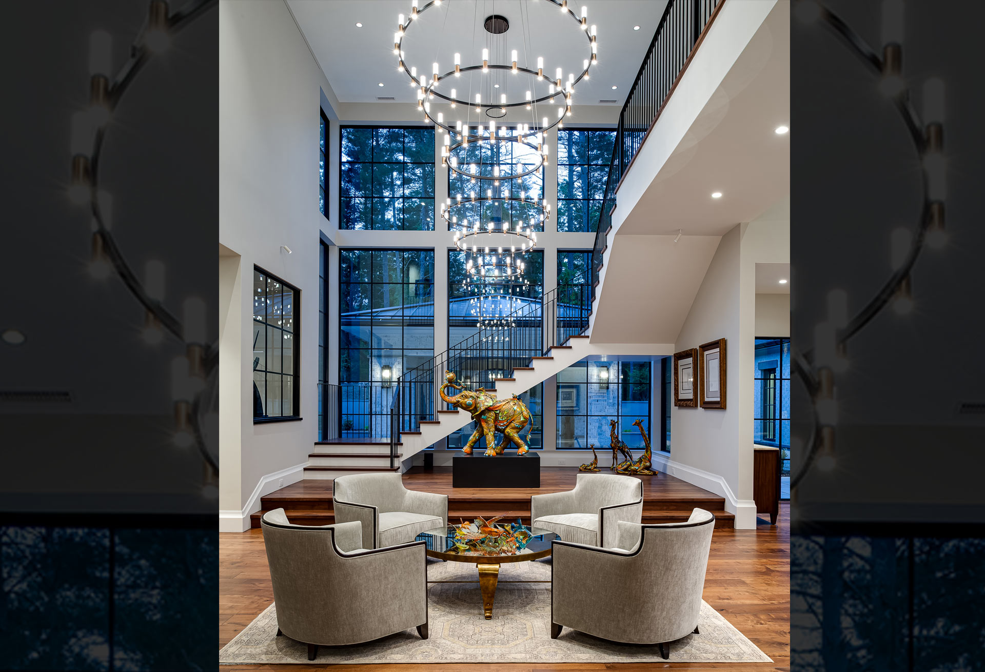 Two-story foyer lounge with modern style floating staircase and wall of windows behind
