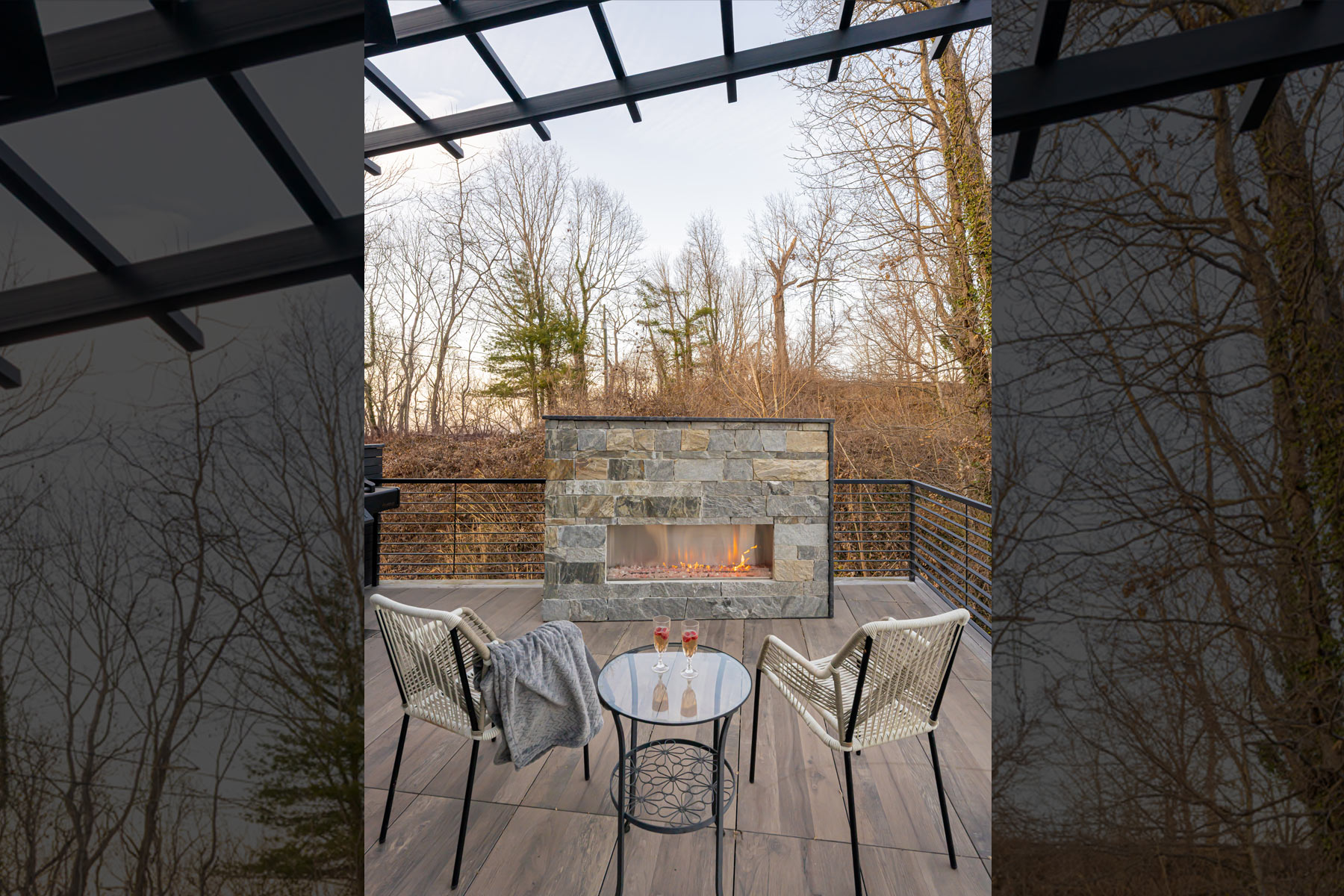 Outdoor fireplace with stacked stone face on deck of newly renovated mountain home in Asheville